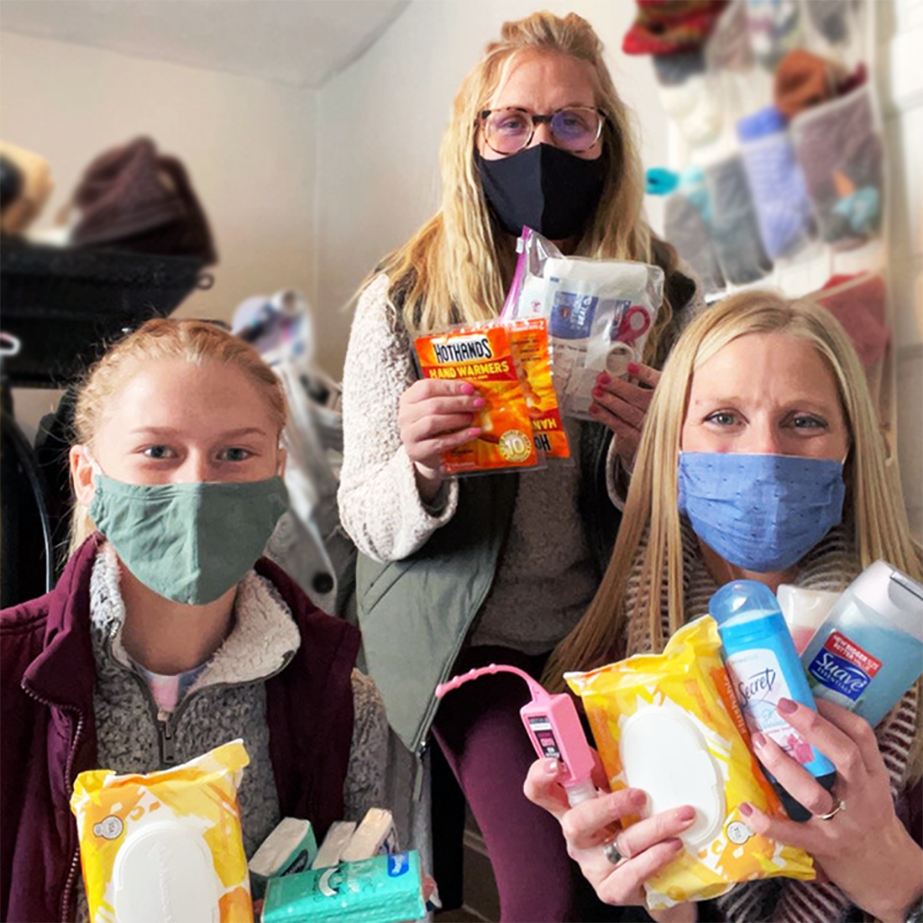 three women smiling and displaying toiletries and personal care supplies in their hands