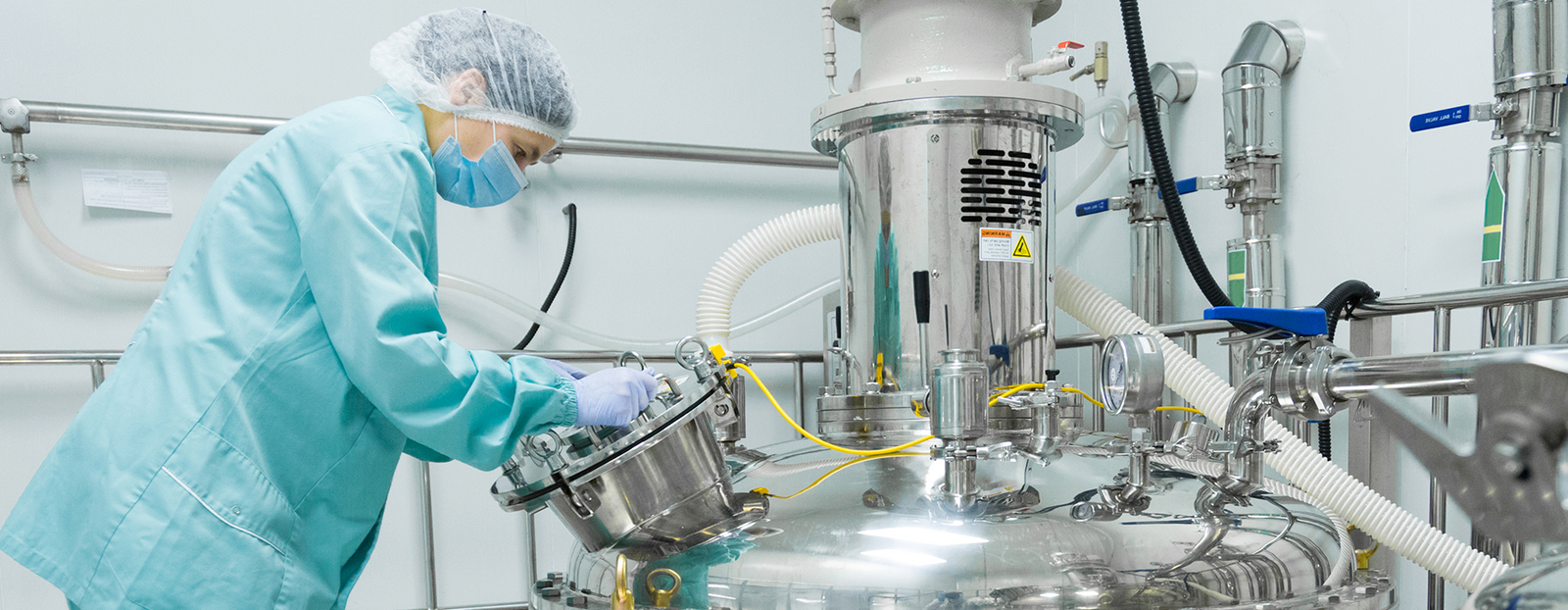 a female lab technician checks manufacturing machinery in a processing plant